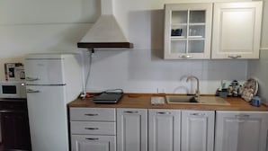 A kitchen with white cabinets, a microwave, a refrigerator, a sink, and a window above the cabinets. - Two Bedroom Apartment (GAMBASSI TERME)
