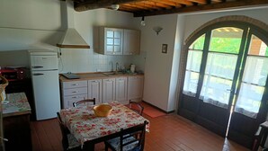 A kitchen with white cabinets, a sink, and a table with a floral tablecloth. - Two Bedroom Apartment (GAMBASSI TERME)