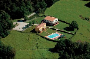 Vue aĂ©rienne dâune propriĂ©tĂ© comprenant une grande maison, une piscine et de nombreux espaces verts.