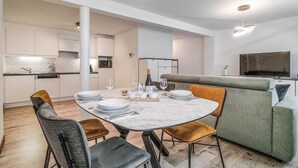 A modern kitchen with white cabinets, a dining table set with plates, glasses, and cutlery. - 1 bedroom awesome apartment in Oostende (Oostende)