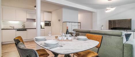 Una cocina moderna con armarios blancos, una mesa de comedor con platos, vasos y cubiertos.