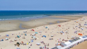 A wide beach with numerous umbrellas and sun loungers, a clear sky, and the ocean in the background. - 1 bedroom awesome apartment in Oostende (Oostende)