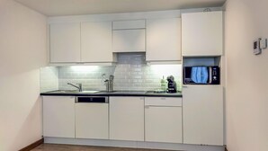 A compact kitchen with white cabinets, a stainless steel sink, a microwave, and a built-in oven. - 1 bedroom awesome apartment in Oostende (Oostende)
