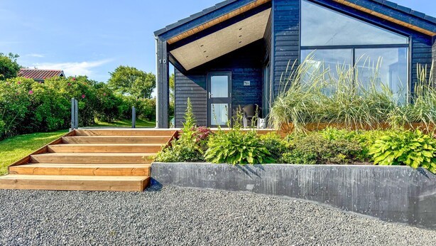Une maison moderne avec un escalier en bois menant à une porte de couleur sombre.