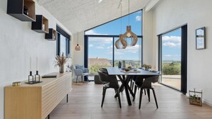 Un espace repas moderne avec une grande fenêtre, une table à manger en bois et des chaises noires.