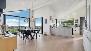 Une cuisine spacieuse dotée d’un grand îlot central, un coin repas offrant une vue agréable et un espace de vie moderne.
