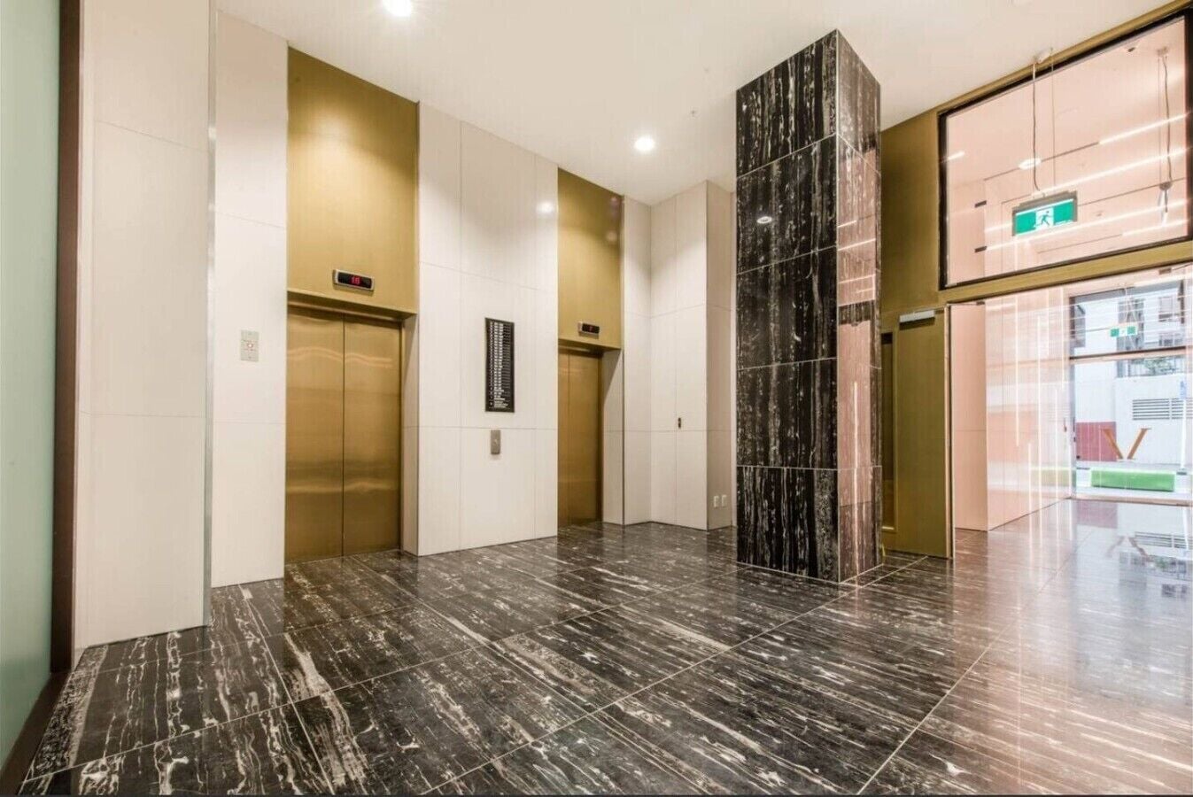 A modern elevator area with marble flooring and a glass wall.