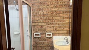 A bathroom with a shower, a sink, and a tiled floor. - ALYN MOTEL (Gunnedah)