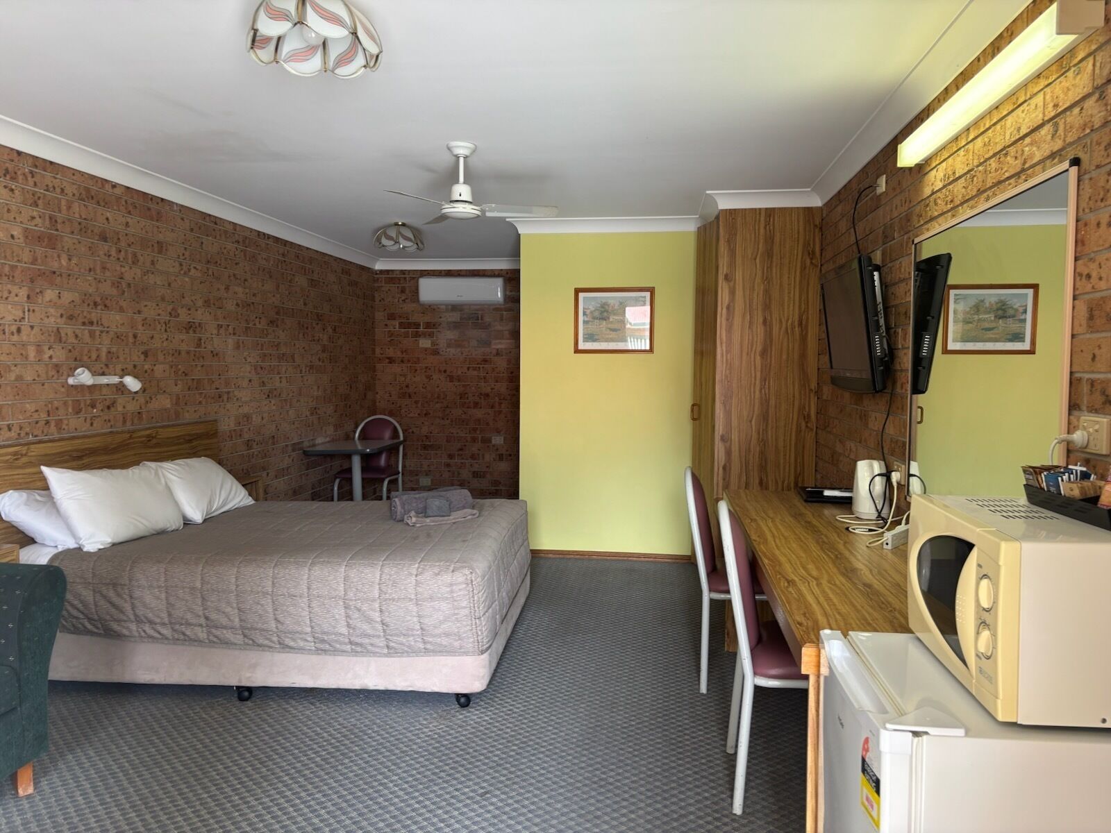 Ein Hotelzimmer mit Bett, Schreibtisch, Stuhl und Fernseher.