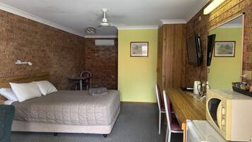 Ein Hotelzimmer mit Bett, Schreibtisch, Stuhl und Fernseher.