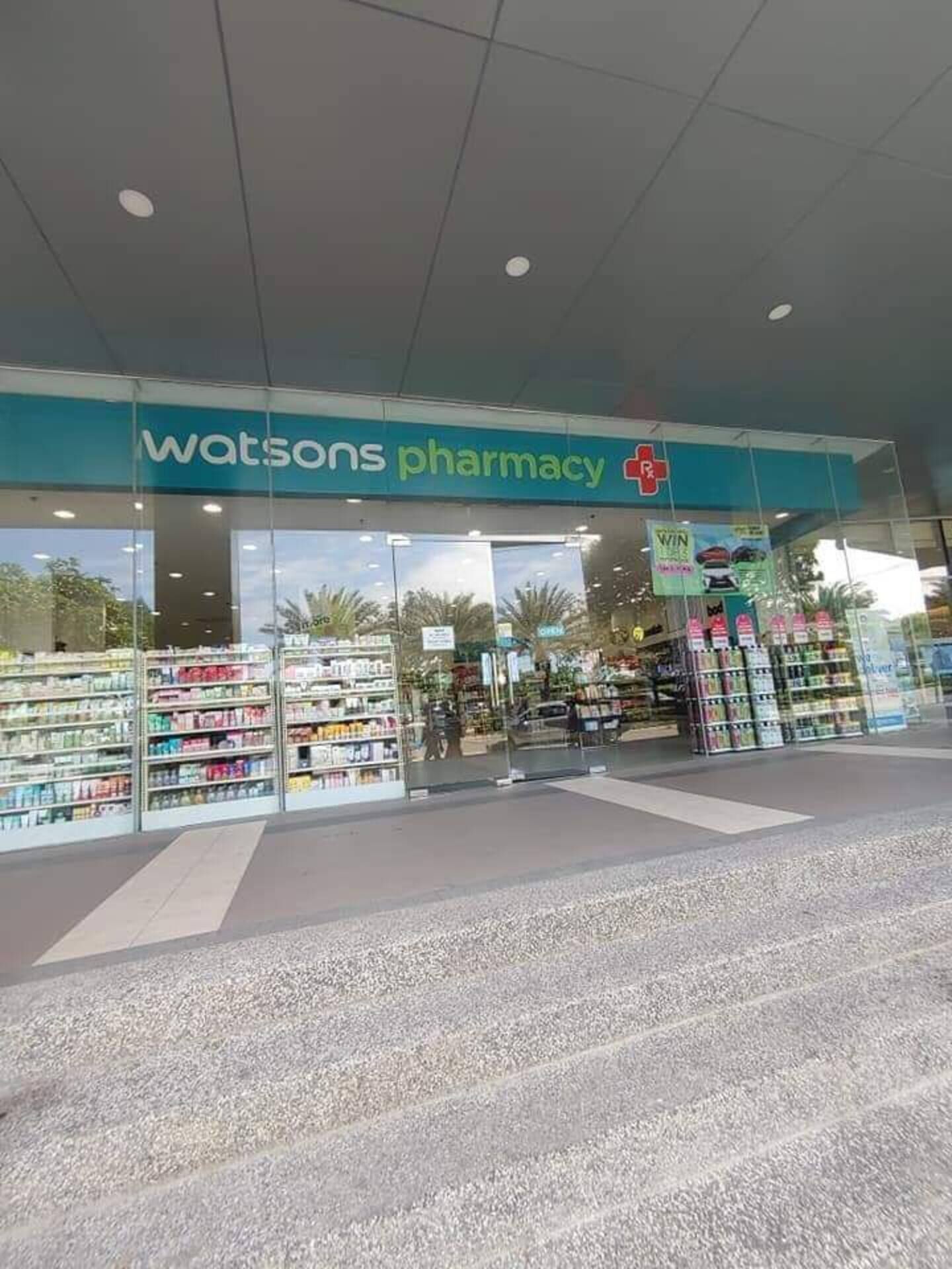 A pharmacy with a clear glass facade, shelves stocked with products, and a sign indicating a promotion.