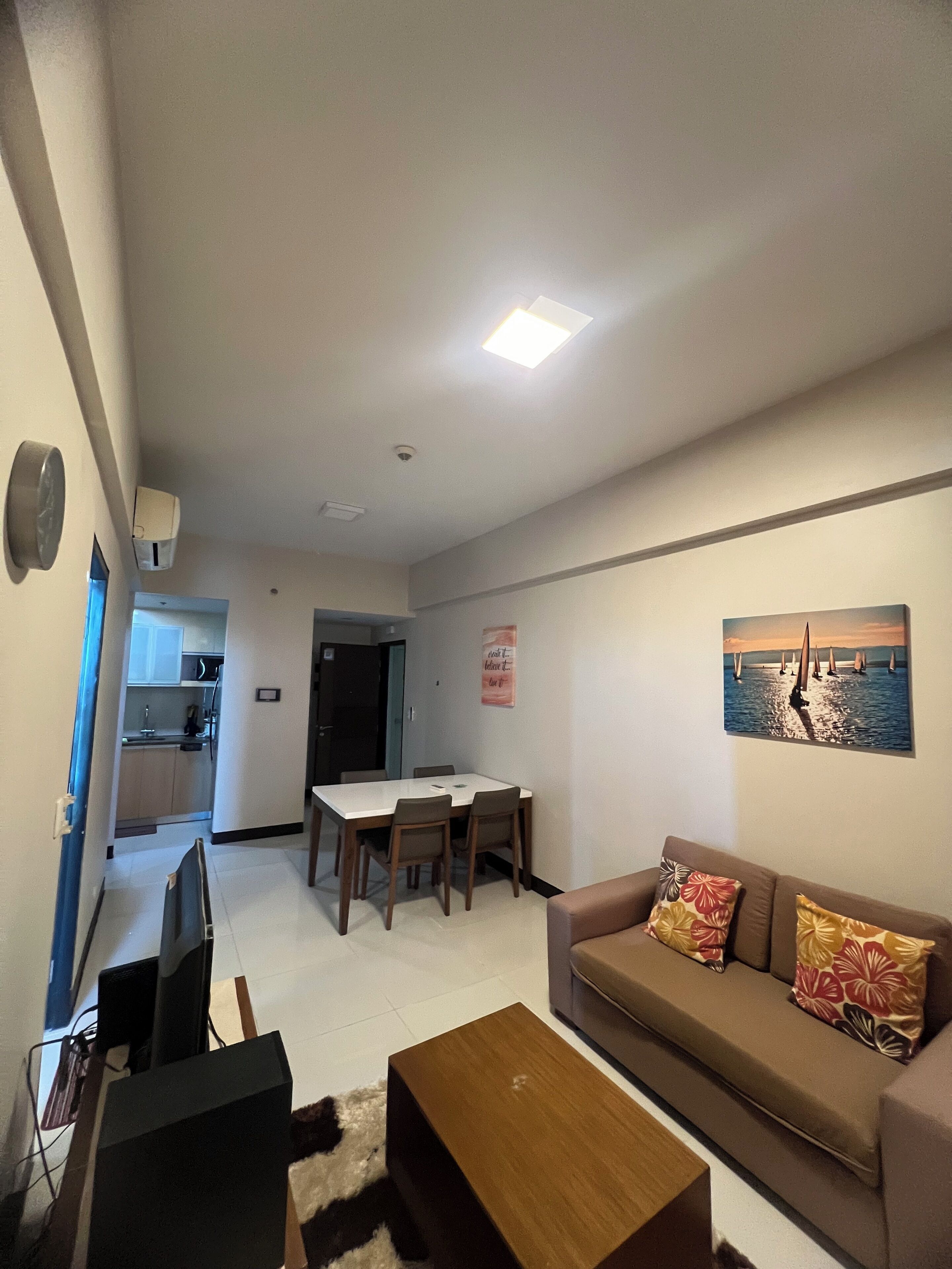 A living room with a sofa, a coffee table, a TV, and a dining area with a table and chairs.