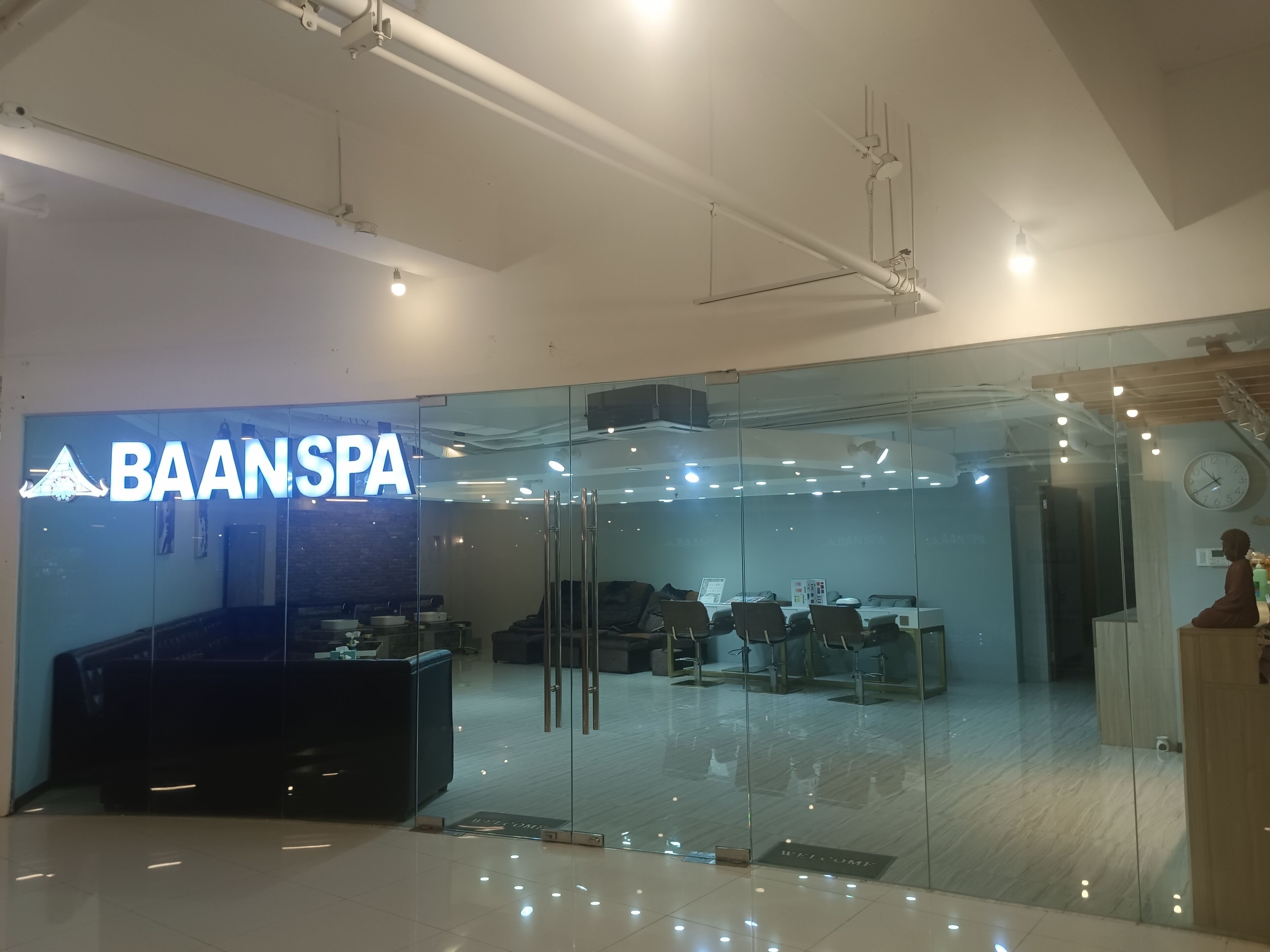 Ett modernt spa med en entré av glas, en receptionsdisk och en klocka på väggen.