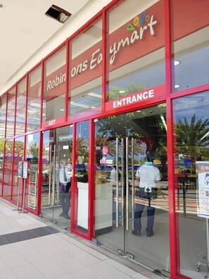 The exterior of a Robin on Earth ymart store with a glass entrance and red signage. - One bedroom Unit at mactan newtown (Lapu-Lapu)