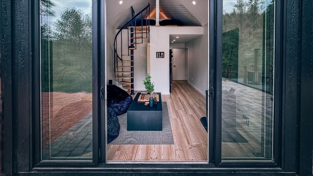 Ein modernes Interieur mit einer Wendeltreppe, einer kleinen Sitzecke mit Schachbrett und einer sichtbaren Tür mit dem Schild "ELM".
