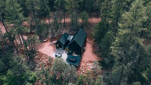 Eine Hütte mit geneigtem Dach, umgeben von dichtem Wald.