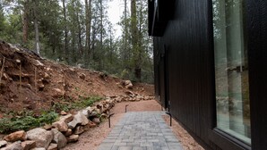 Ein gepflasterter Weg führt zu einem modernen Gebäude, begleitet von einer Stein-Stützmauer.