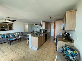 A spacious living area with a sofa, a coffee table, and a kitchen with wooden cabinets and a granite countertop.