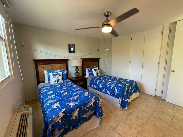 A bedroom with two beds, a ceiling fan, a heater, and a wardrobe.