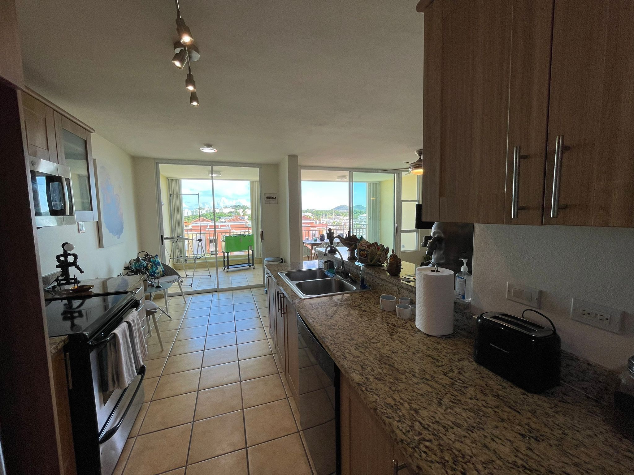 A modern kitchen with granite countertops, stainless steel appliances, and a view of the cityscape through large windows.