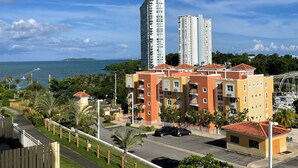 Un quartier résidentiel comprenant deux immeubles à appartements de grande hauteur, un parking et une vue sur la mer.