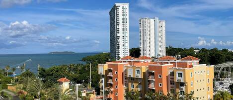 Zona residencial com dois edifícios de apartamentos altos, um parque de estacionamento e vista para o mar.