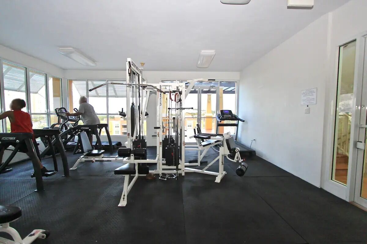 Une salle de sport équipée de divers appareils d’exercice, dotée de grandes fenêtres et d’un intérieur propre et moderne.