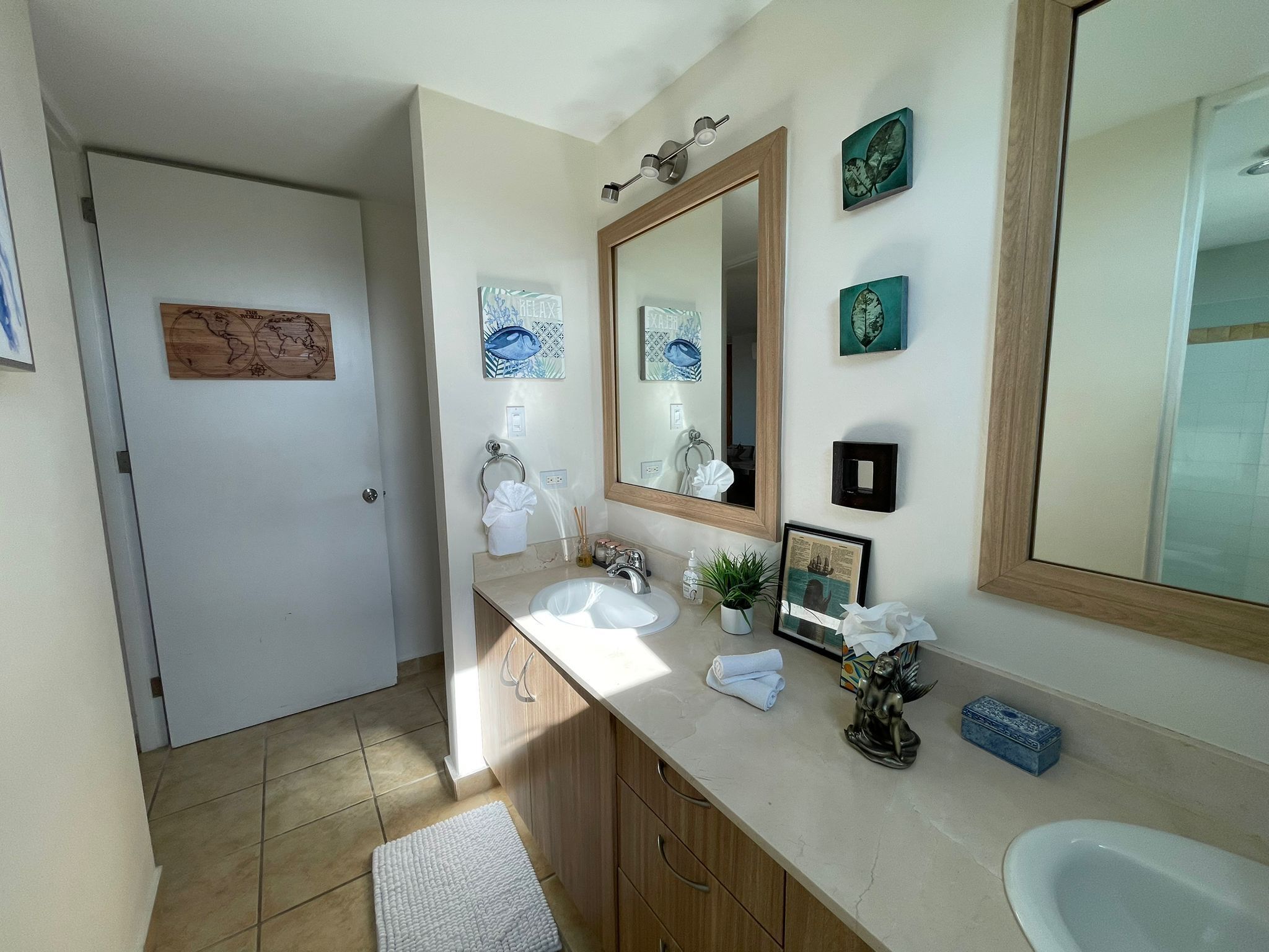 Une salle de bain avec un grand miroir, deux lavabos, un porte-serviettes et des objets décoratifs sur le comptoir.