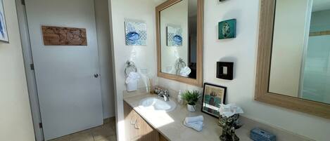 Une salle de bain avec un grand miroir, deux lavabos, un porte-serviettes et des objets décoratifs sur le comptoir.
