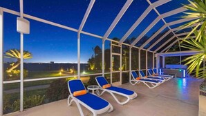 Un espacio al aire libre techado con sillones de descanso y vistas al cielo nocturno.