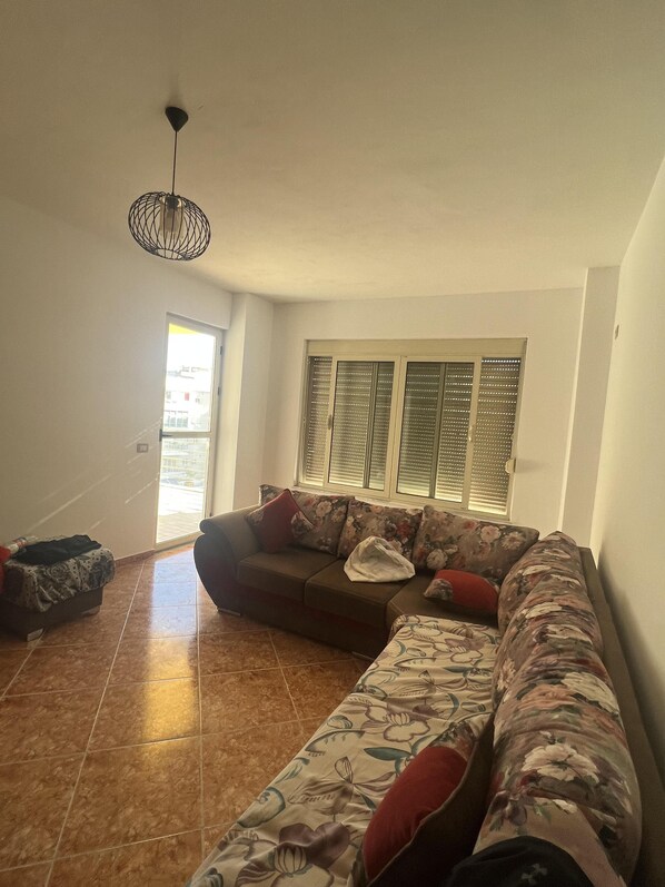 Uma sala de estar com sofá modular, uma mesinha e uma luminária no teto.