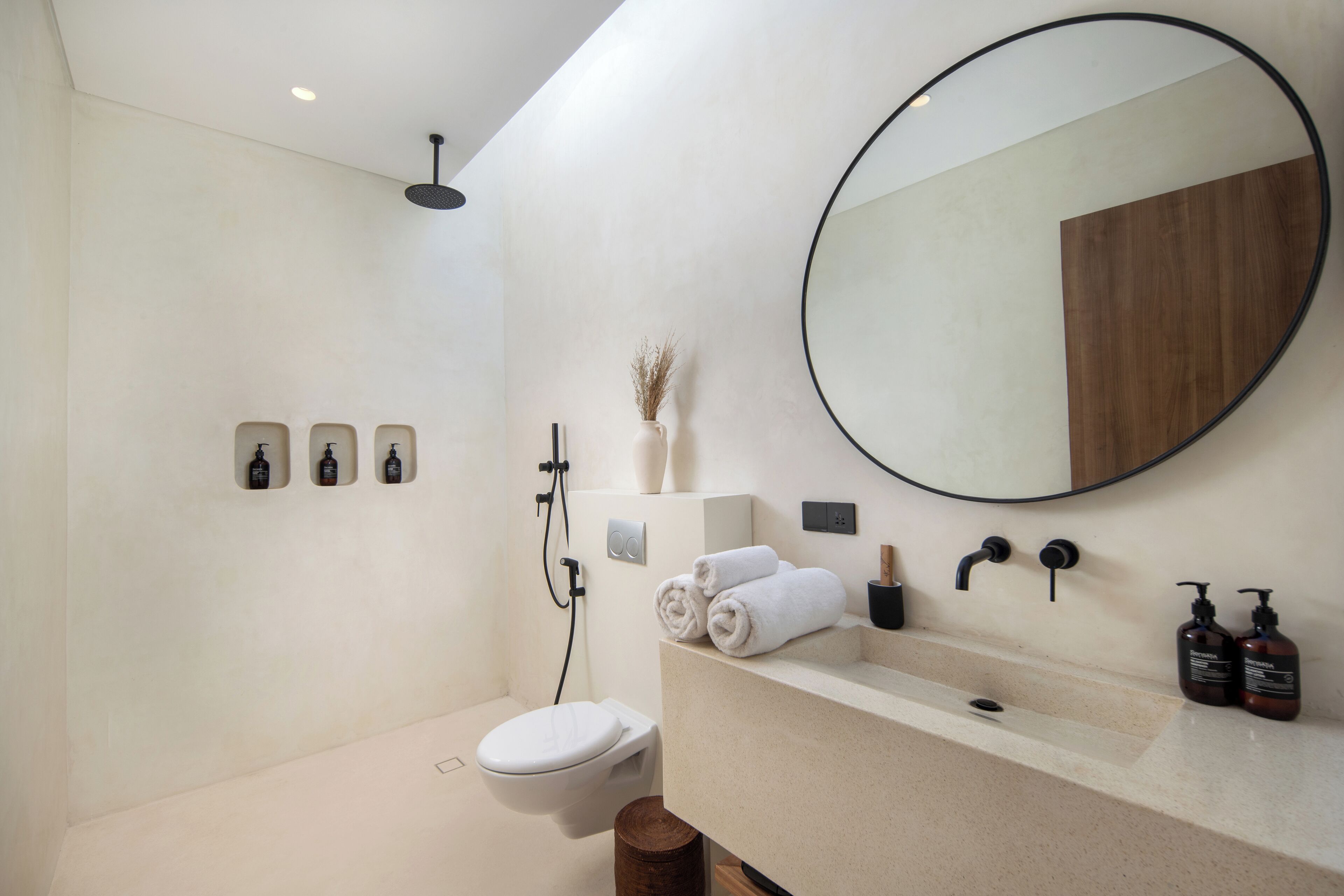 A modern bathroom with a toilet, sink, mirror, and shower.