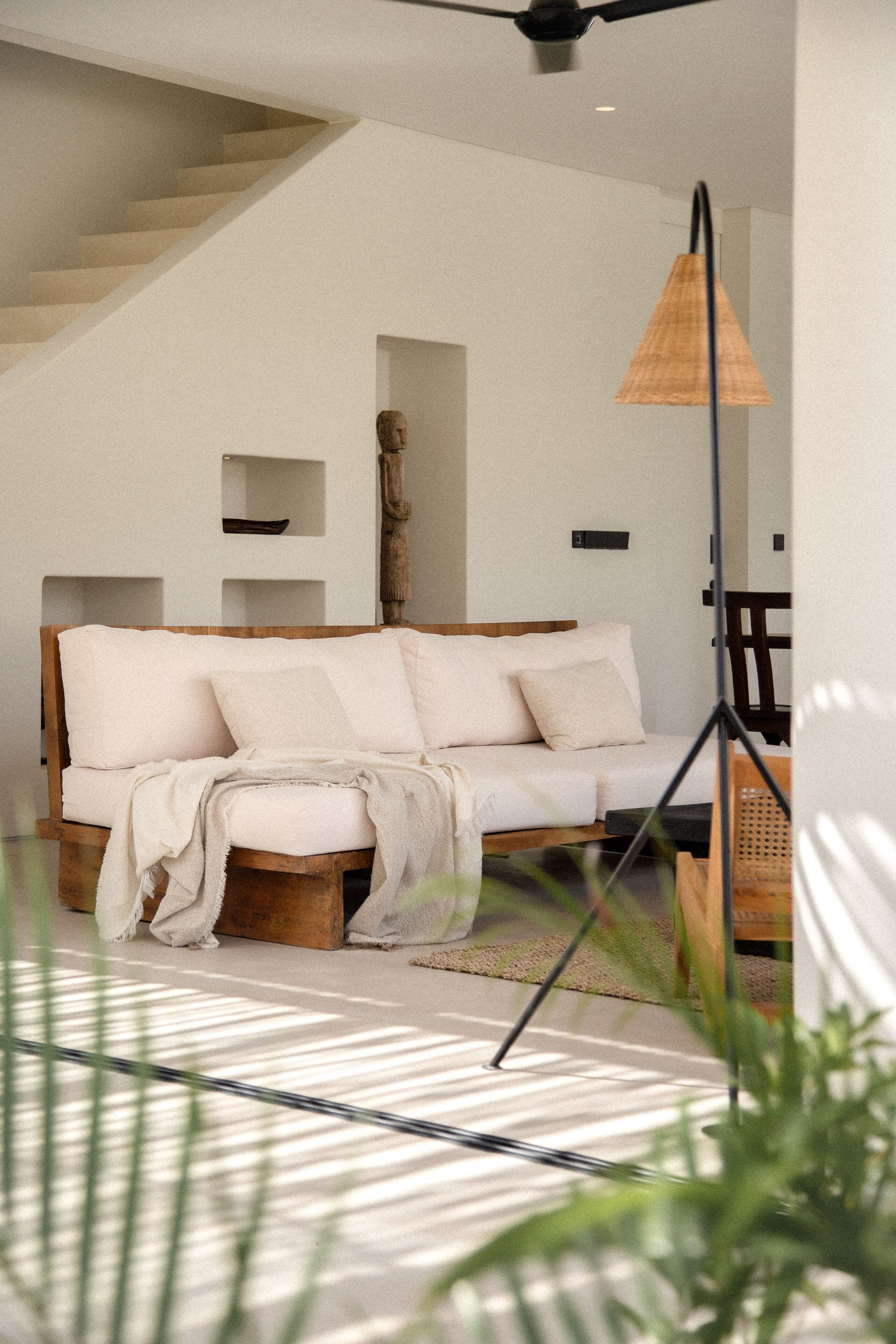 Una sala de estar moderna con un sofá de madera, una lámpara de pie y una escalera.