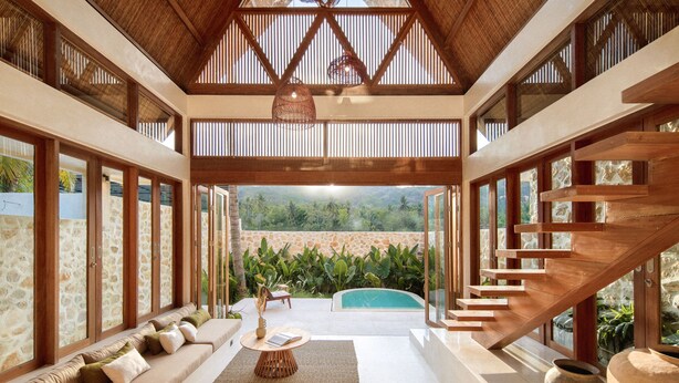 Un vaste espace de vie agrémenté d’un escalier en bois, d’une piscine et offrant une vue sur la verdure.