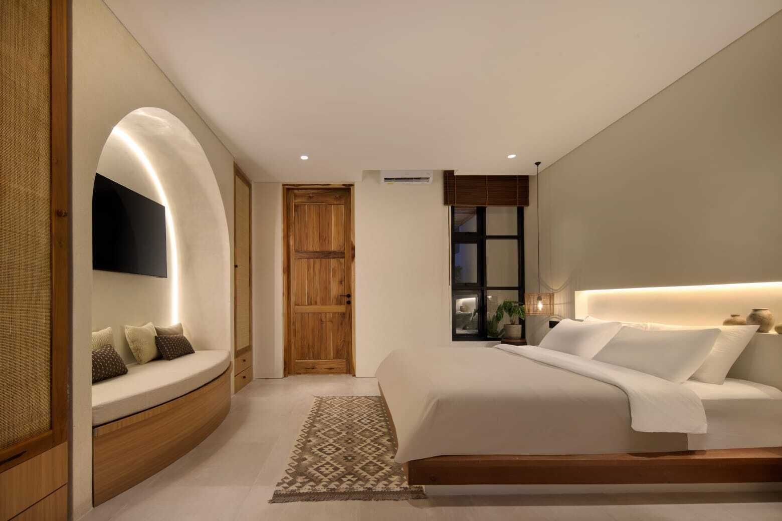 Un dormitorio moderno con una cama grande, un banco empotrado, un televisor en la pared y un ventanal con vistas.