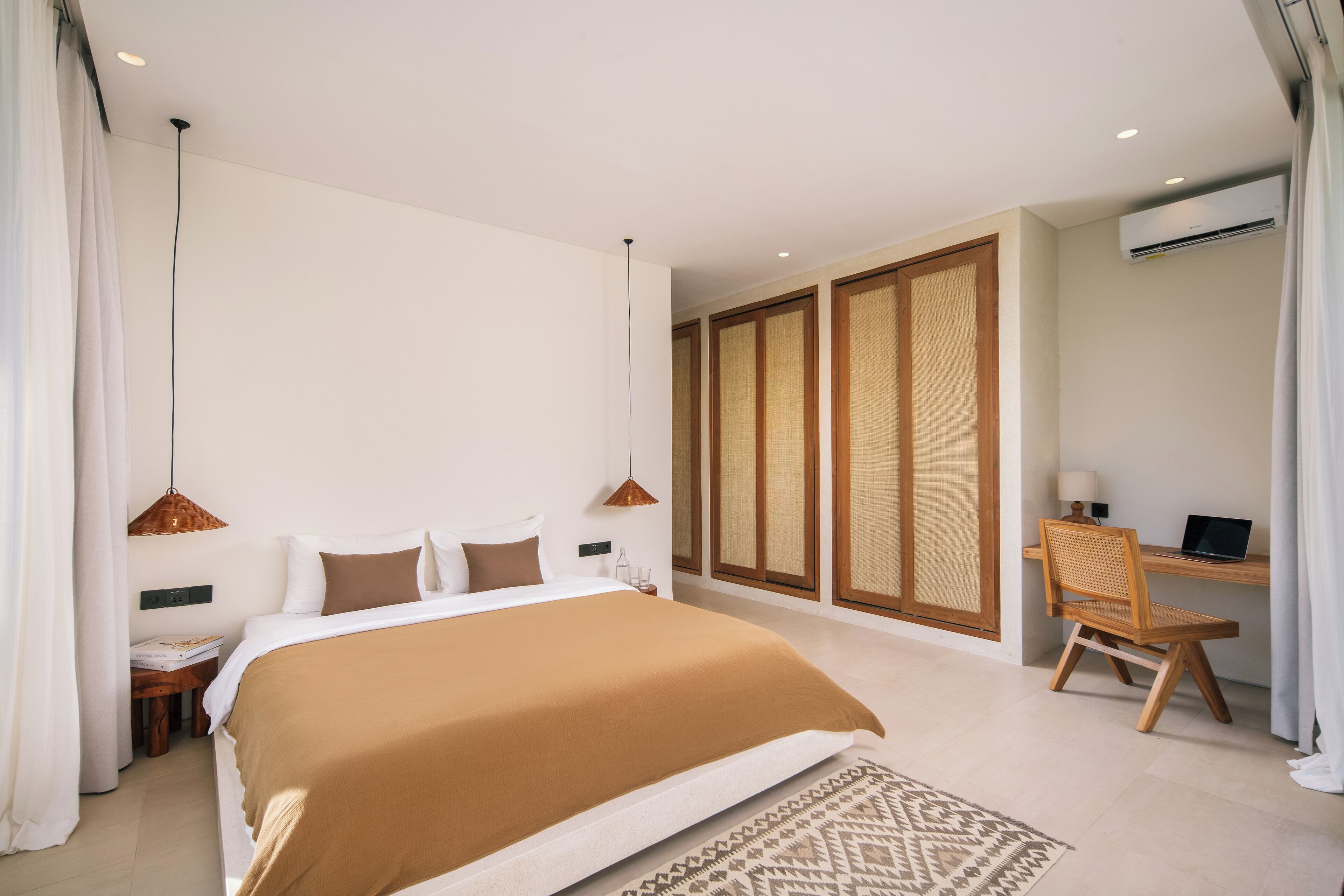 Um quarto moderno com uma cama grande, uma escrivaninha com cadeira e um aparelho de ar condicionado.
