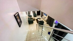 Un espace de vie moderne comprenant un escalier, un téléviseur à écran plat et un canapé.