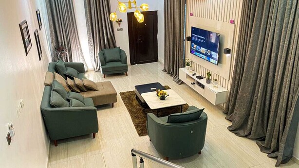 Un salon moderne avec un canapé d’angle, une table basse et un téléviseur fixé au mur.