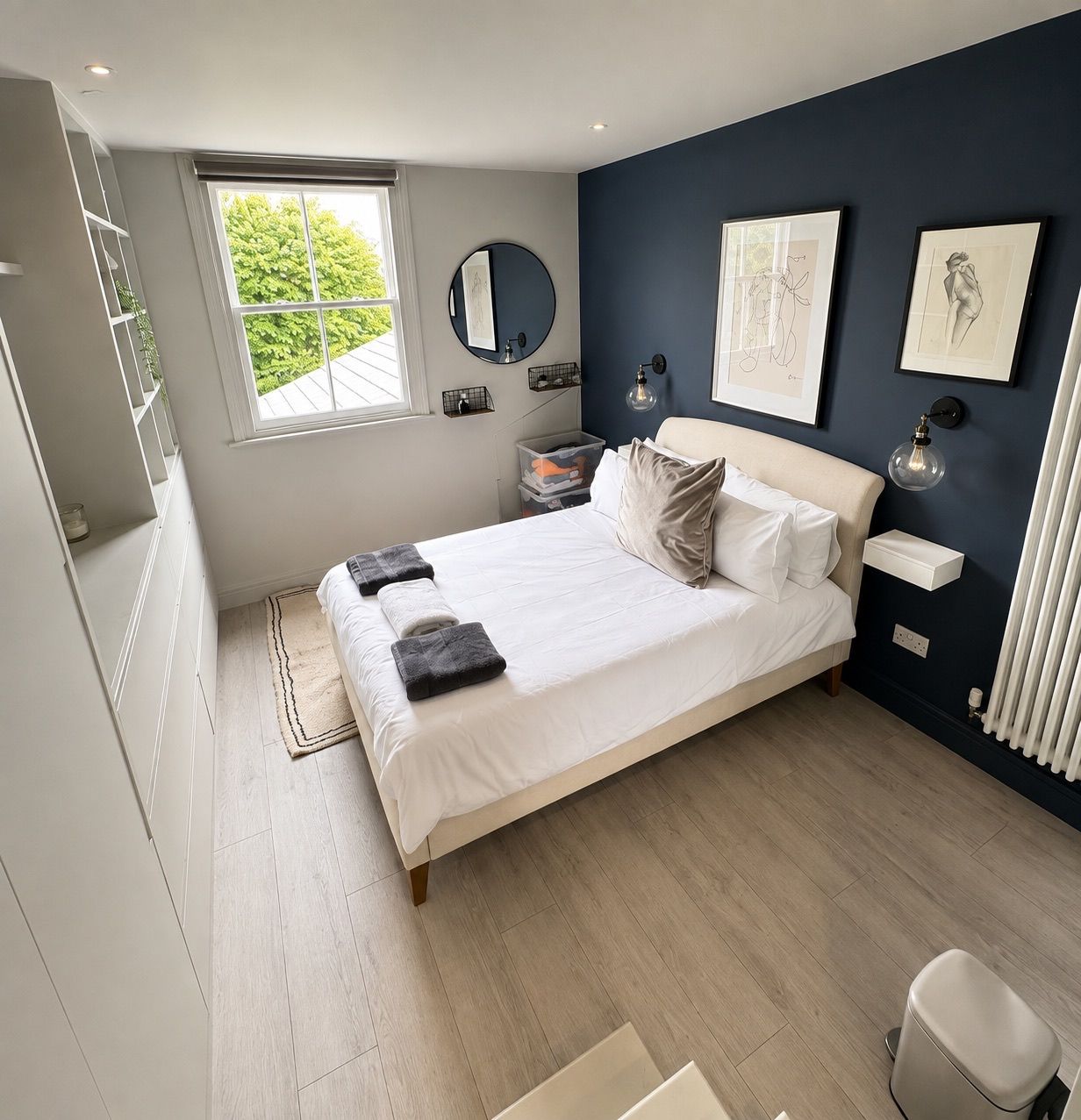 A modern bedroom with a large bed, a bedside table, a mirror, and artwork on the wall.