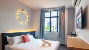 A hotel room with a bed, a TV, a window with curtains, and a wall-mounted air conditioner. - Ink Hotel by ALV (George Town)