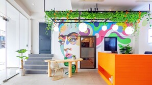 A reception area with a colorful mural, a reception desk, a staircase, and a seating area with a table and chairs. - Ink Hotel by ALV (George Town)