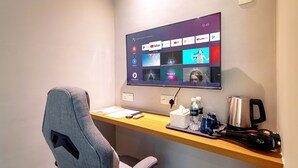 A modern office space with a desk, a chair, a mounted TV displaying various streaming services, and a coffee maker. - Ink Hotel by ALV (George Town)