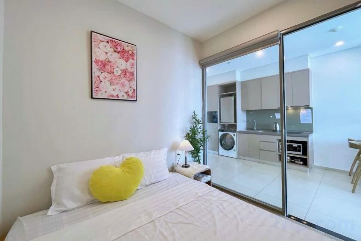 A bedroom with a bed, a nightstand, a lamp, and a window.