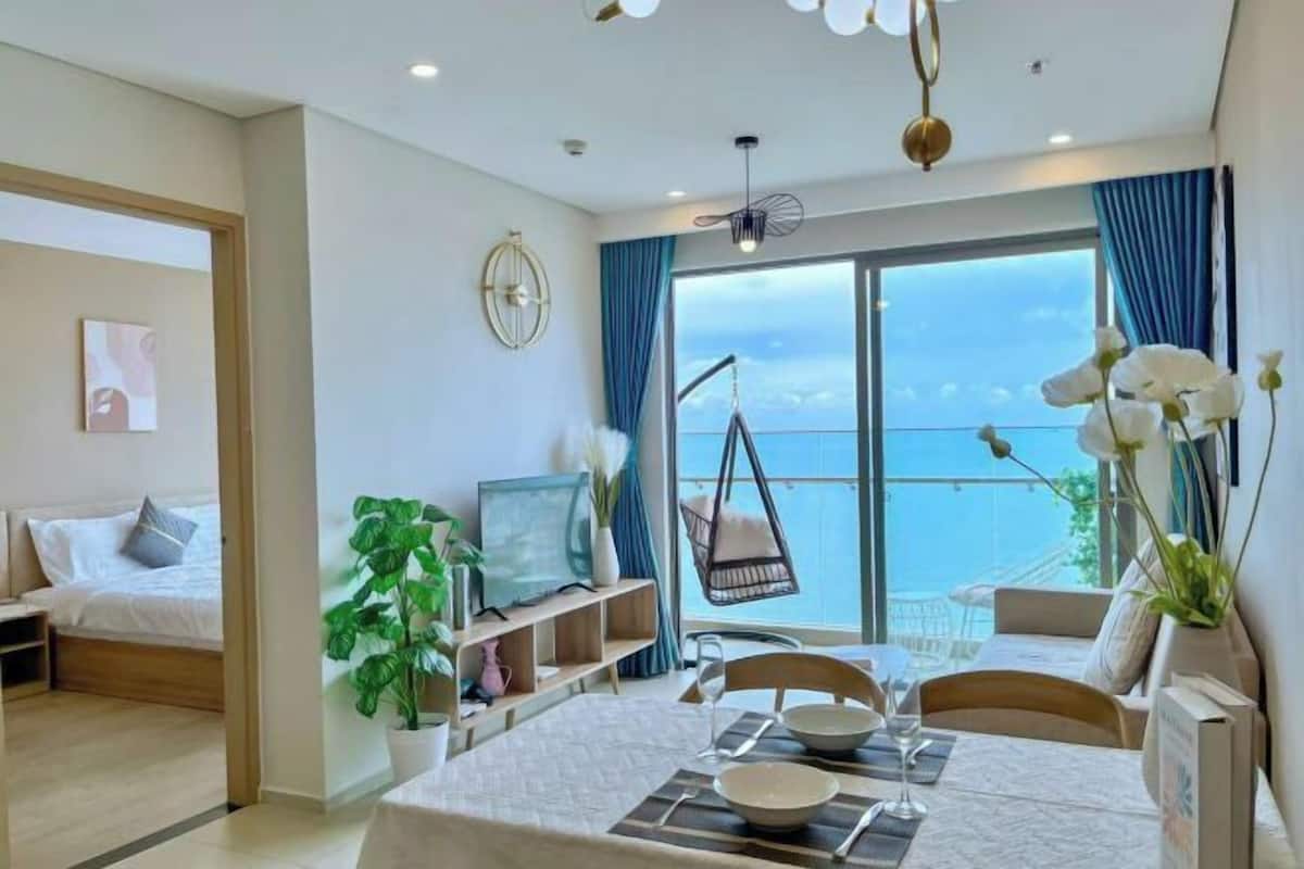 A modern hotel room with a balcony, a dining area, and a bed.
