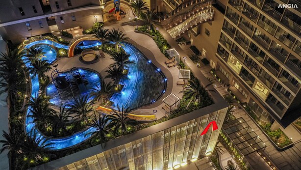 Oversigtsbillede af et hotel med swimmingpool, palmer og moderne arkitektur.