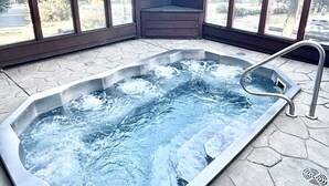 Een jacuzzi in een hoek met uitzicht op bomen en een bord waarop staat dat het zwembad een capaciteit heeft voor 8 personen.