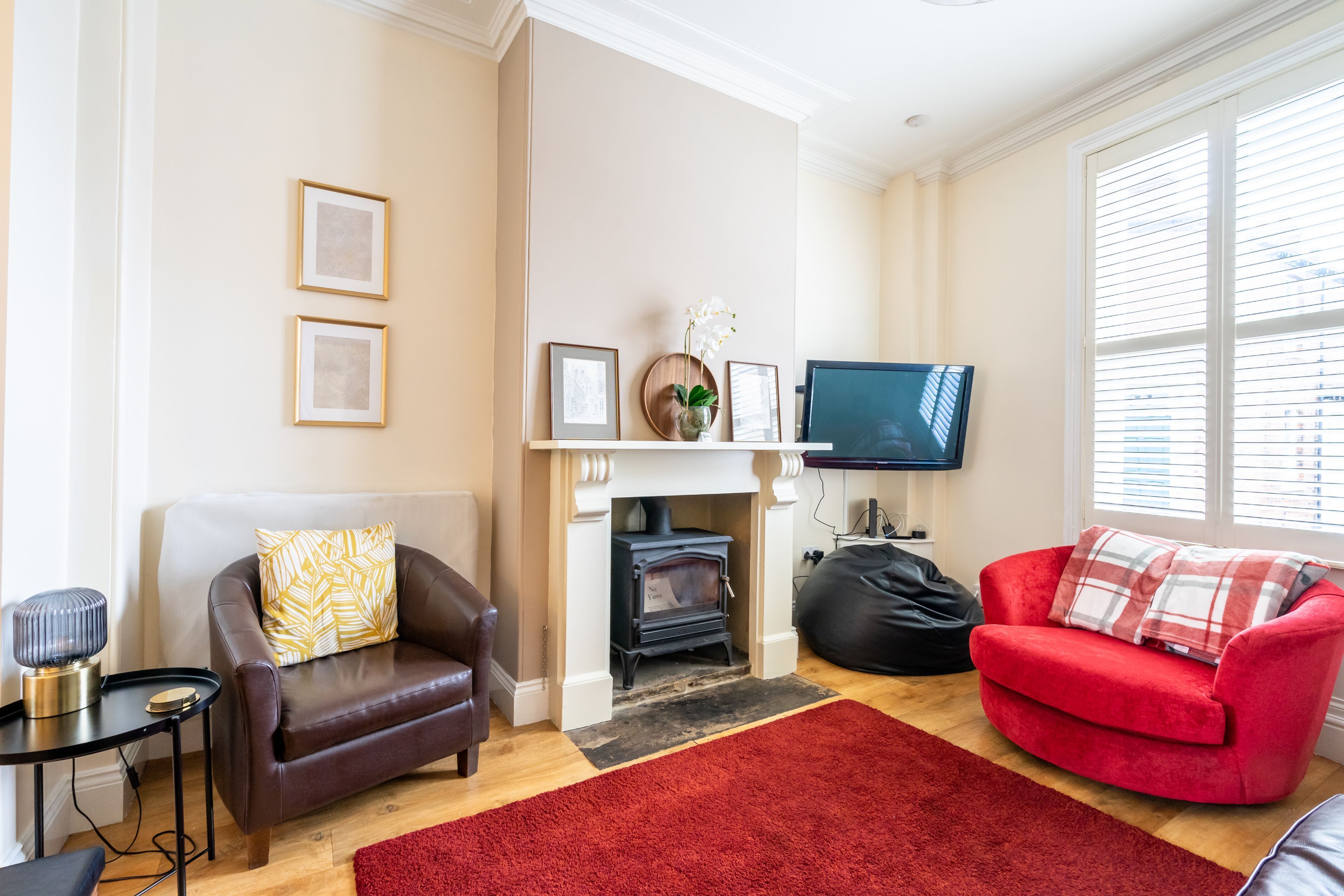 A living room with a fireplace, a red couch, a brown leather sofa, and a television.