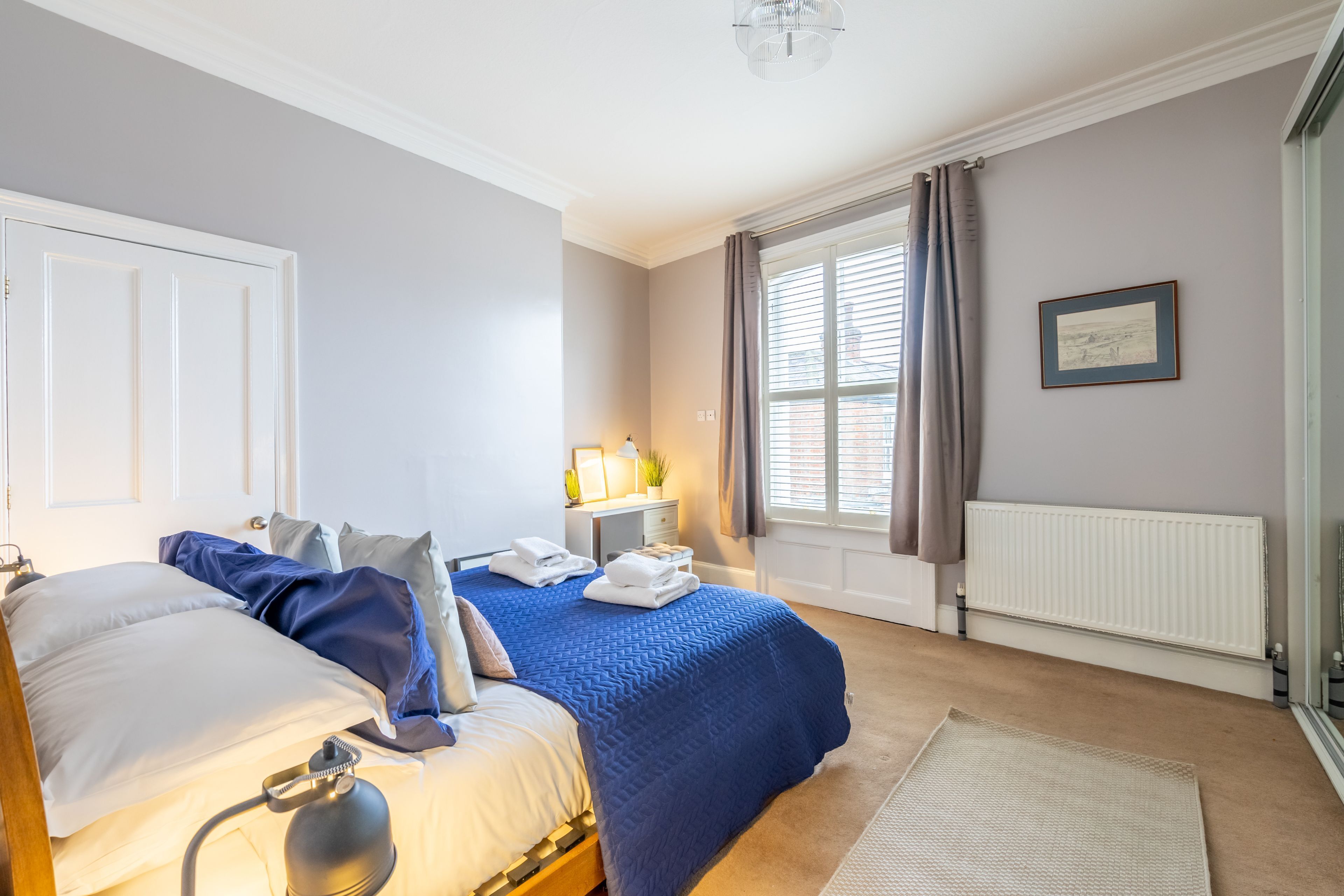A bedroom with a bed, bedside table, lamp, and a window with curtains.