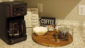 A kitchen with a coffee maker, a sign with coffee-related rules, and a tray with a jar and a bowl. - Clean Comfy Cottage - Near Downtown High Point Furniture Market, Hospitals & HPU (High Point)