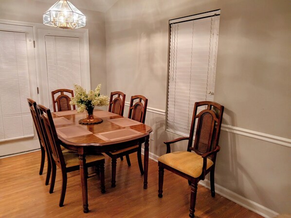 A dining room with a wooden table, six chairs, and a chandelier.